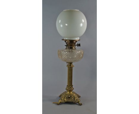 A Victorian brass oil lamp, with moulded glass reservoir, above fluted column, on strap work pierced square stand, on lions p