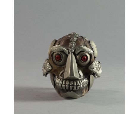 A white metal mounted monkey skull, 19th/20th century, probably Tibetan, decorated in a naturalistic manner with eyes and hai