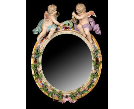 A 19th Century Meissen porcelain small circular dressing table mirror with two cupids atop, the easel back with blue crossed 