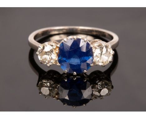 A sapphire and diamond three stone ring, the central circular sapphire flanked by a diamond to each side, the sapphire 7.3mm 