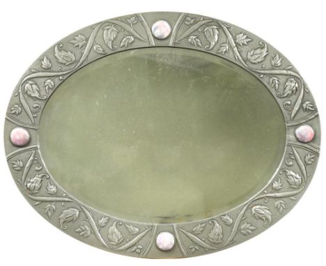 An Arts &amp; Crafts pewter oval bevelled wall mirror, the frame with hand-beaten and repousse twisting foliate design, and f