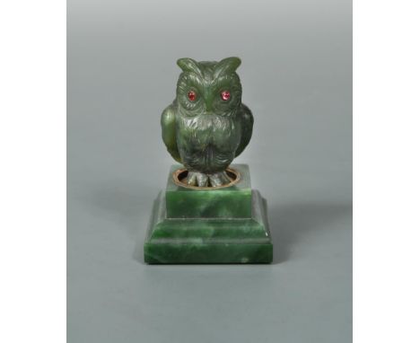 A jade and gem-set model of an owl in the manner of Fabergé, the carved jade owl with ruby eyes a circular brass base inset t