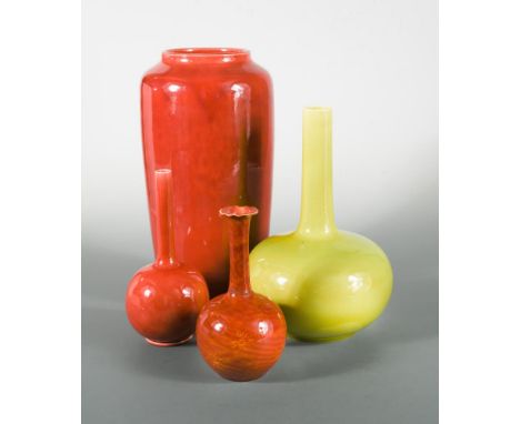 Four Burmantofts faience vases, comprising a yellow glaze bottle vase, a large red glaze vase, and two small red glaze bottle