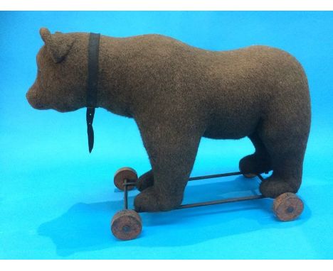 An early 20th century pull-along 'Growling' bear (probably Steiff), straw filled, standing on a cast iron frame, with four wo