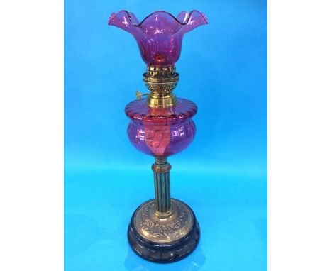 A Victorian oil lamp with cranberry reservoir and shade