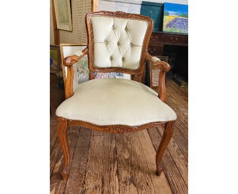 A button back chair upholstered in cream fabric, wooden arms, overstuffed seat over cabriole legs.