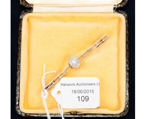 An Edwardian yellow metal opal set bar brooch, the central opal claw set with an open back, the body of the brooch with scrol