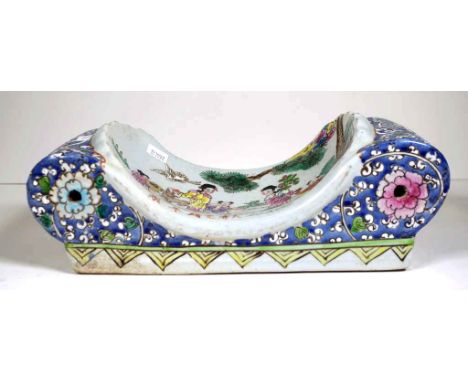 Chinese decorated ceramic pillow decorated with figures in a garden, and flowers on blue ground. (length 30cm approx, height 