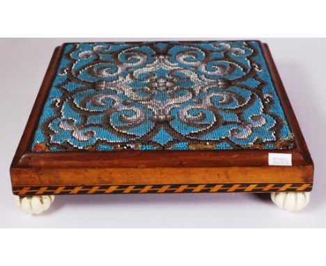 Antique bead decorated tapestry kneeler (small losses to bead embroidery), banded decoration to wood base, on 4 ceramic feet.