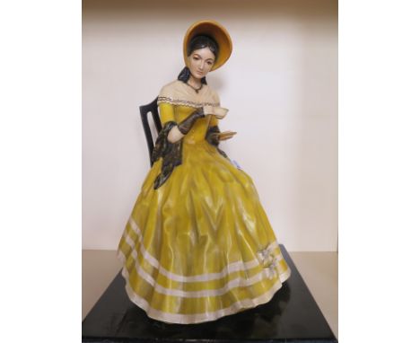 A large countertop figurine of a seated lady with tea cup, dressed in 19th century clothes, lacquered composite figure, with 