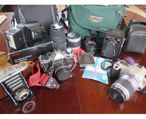 A collection of cameras and camera accessories, a Canon AE-1, a Canon EOS 300 a vintage Agfa Isolette II, a Lubitel Unversal 