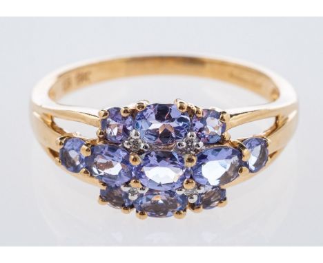 A 9ct yellow gold cluster design ring, set with circular-cut and oval-cut tanzanites and four small brilliant-cut diamonds, U