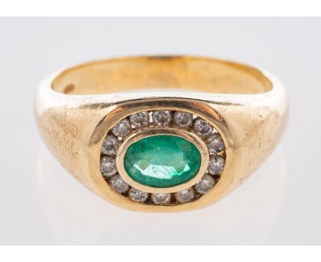 An emerald and diamond ring, a signet style ring set 'east to west' with an oval-cut emerald, surrounded by small brilliant-c