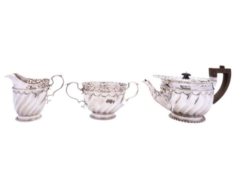 A Victorian three piece silver tea service by Goldsmiths and Silversmiths Co. Ltd, London 1898, swirl fluted body, openwork b