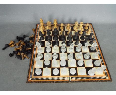 Three chess sets to include a glass set with 7.5 cm king and two wooden set, the larger with 8.5 cm king, also includes a fol