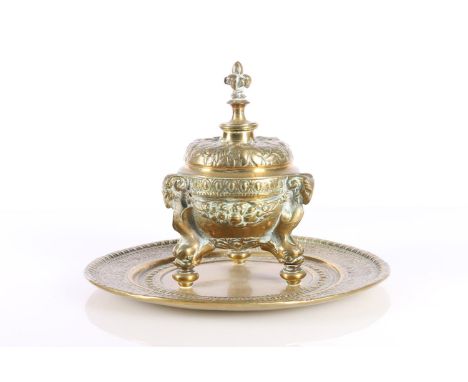Indian brass inkwell raised on ram mask and dolphin supports, 19cm diameter. 