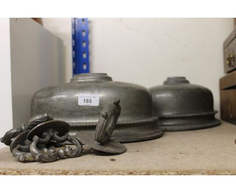 Two white metal meat covers and a cast metal table clock. The handles do not appear to match.