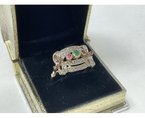 An Edwardian 14ct gold dress ring set with a display of old cut diamonds, rubies and a central emerald. Size V.