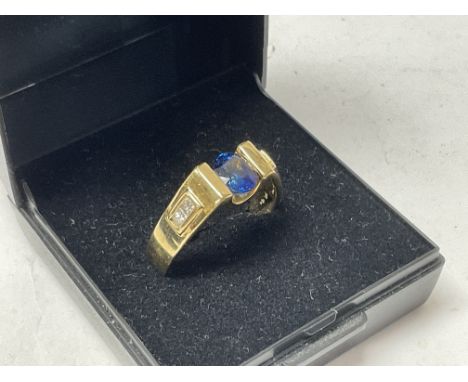 A modern 18ct yellow gold ring set with a central sapphire, the shoulders inset with 4 Princess cut diamonds. K.