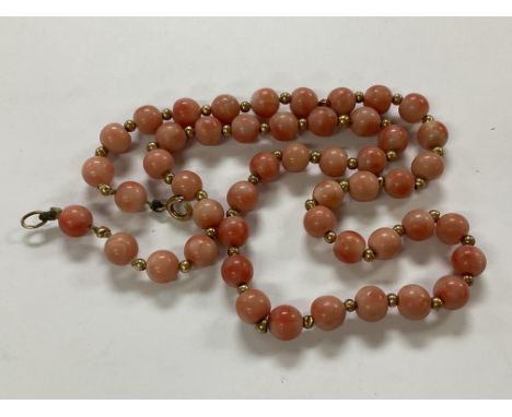 A string of pink coral beads spaced with 9ct gold beads.