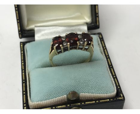 A 1970s style 18ct yellow gold ring set with 3 oval cut garnets and 4 small diamonds, Size O.