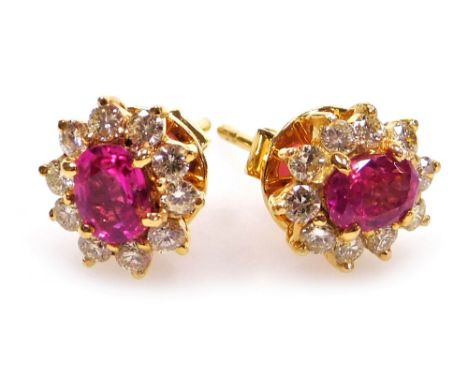 A pair of ruby and diamond cluster earrings, the central facet cut ruby of 6.1mm x 5.2mm surrounded by ten round brilliant cu