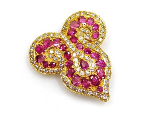 A ruby and diamond set brooch, of Eastern scroll shape set with twenty seven oval faceted rubies ranging in size from 1.3mm t