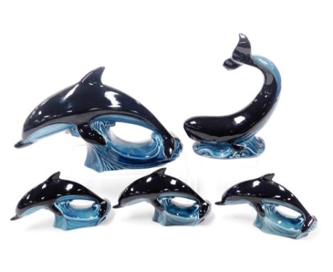 A Poole pottery figure of a dolphin, modelled riding the crest of a wave, three smaller figures of dolphins, and a figure of 