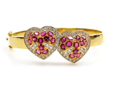 A ruby and diamond set hinged bangle, with two heart shaped motif to the front, each set with twelve rubies of 1.9mm approx, 