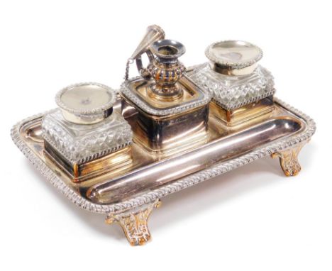 An early 19thC silver plated desk stand, with two pen recesses, pair of cut glass inkwells, with hinged lids, flanking a cent