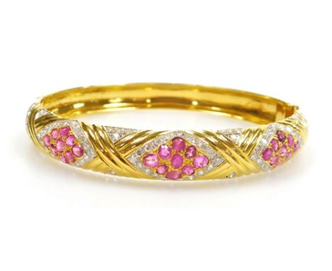 A ruby and diamond set hinged bangle,  three ruby set lozenge shaped motifs of nine stones of 2mm each, surrounded by tiny di