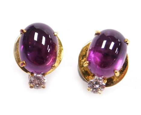 A pair of oval cabachon ruby and diamond stud earrings, the purple hue ruby of .4mm x 5.8mm approx topped by a round brillian