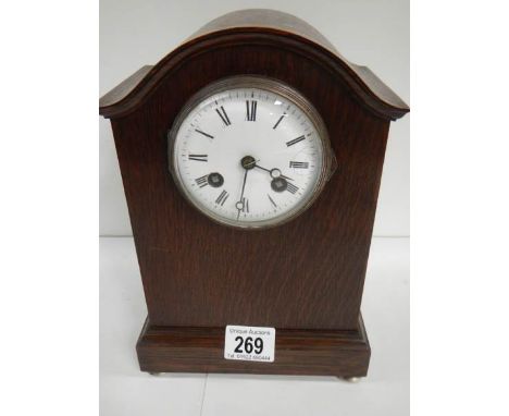 An oak mantel clock in working order complet with key and pendulum (chip on face)