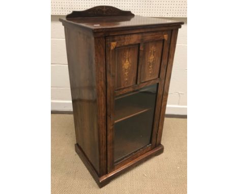 A late Victorian rosewood and marquetry inlaid music cabinet, the part glazed door enclosing four shelves, raised on a bracke