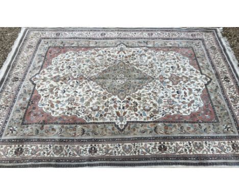 A Persian carpet, the central panel set with floral decorated medallion on a mushroom, cream and pale pink ground, within a s