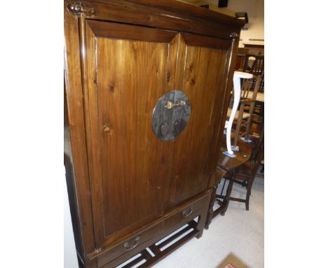 A Chinese cherrywood wedding cabinet, the two panelled cupboard doors opening to reveal two shelves on a base with two drawer