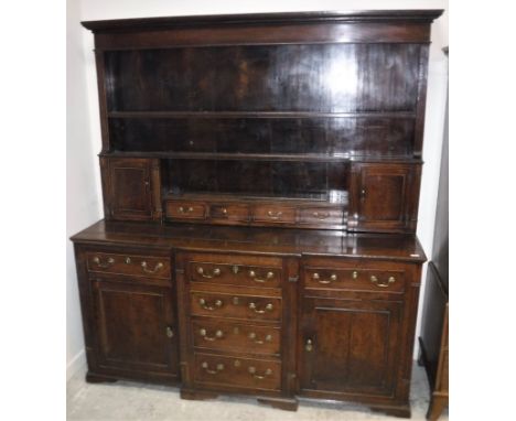 A George III oak dresser, the boarded three tier plate rack with four central drawers flanked by two small cupboard doors ove