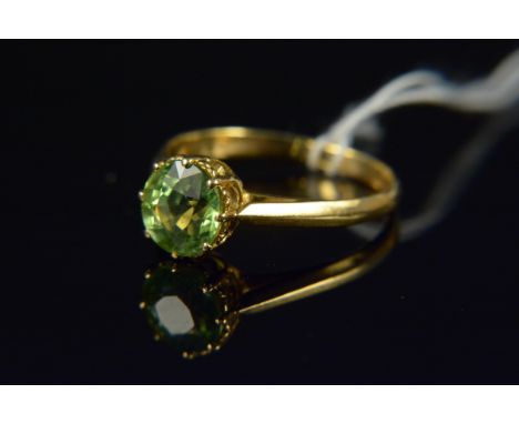 An unmarked yellow gold single peridot set ring, the round faceted peridot in eight claw setting, size O, weight approx 2.5g