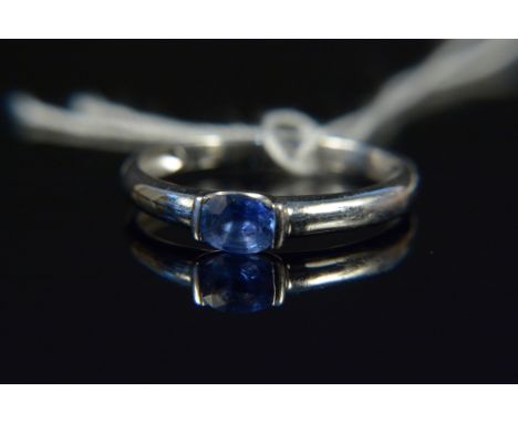 A white gold single sapphire set ring, the oval cut sapphire in partial rub over setting, size R, weight approx 2g (hallmarks