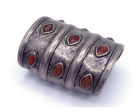 A North African white metal and carnelian cuff bangle, with engraved three-band construction, 8.8cm long CONDITION: one gem c