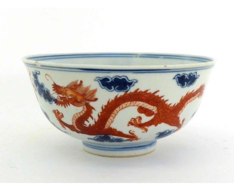 A Chinese porcelain dragon bowl with flared rim, deep sides on circular foot rim, iron red decoration of dragon chasing flami