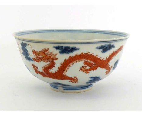 A Chinese porcelain dragon bowl with flared rim, deep sides on circular foot rim,  iron red decoration of dragon chasing flam