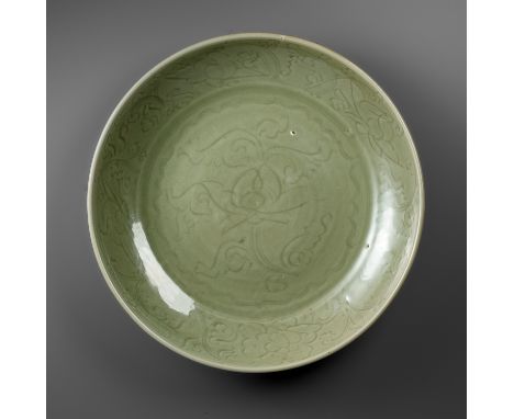A MASSIVE CARVED 'LOTUS' LONGQUAN CELADON CHARGER, EARLY MING DYNASTYChina, 15th-16th century. The broad rounded sides rising