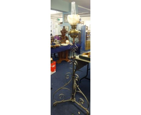 A Victorian ornate cast iron floor standing oil lamp stand with a brass oil lamp