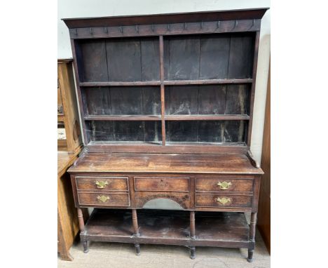 An 18th century South Wales oak dresser, the rack with a moulded cornice and three shelves, the base with an arrangement of t