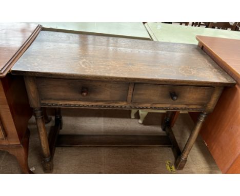 An oak side table with a rectangular top above two drawers on ring turned column legs and stretchers 