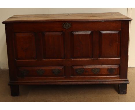 An 18th century oak coffer with a planked rectangular top above a four panel front with faux drawers on stiles, 143cm wide x 