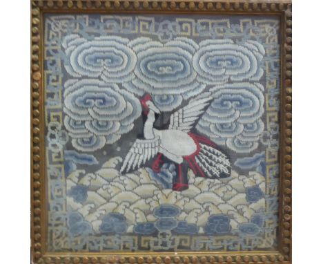 A C19th Chinese silk embroided emblem with scrolling clouds with central bird on waves with repeating Greek key surround fram