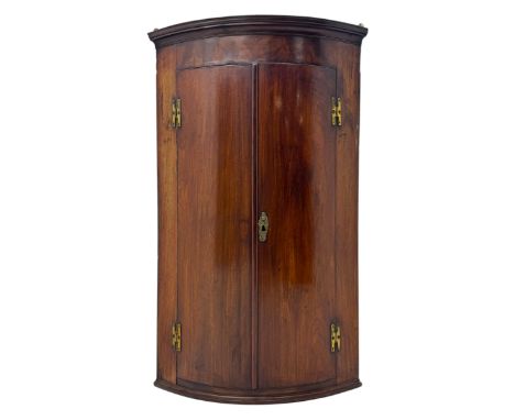 Late Georgian mahogany hanging corner cupboard, bow-fronted form with moulded cornice over a pair of panelled doors enclosing
