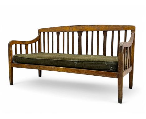Early 20th century oak bench, the back formed of vertical slats, gently curved arms, and a removable seat cushion in green st